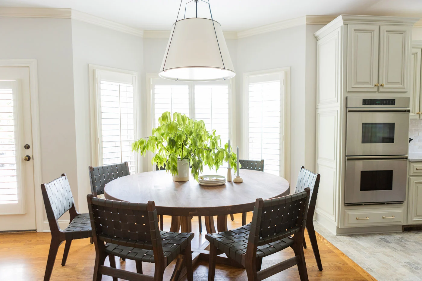 Gweneth breakfast area with round table, woven chairs, and double wall ovens