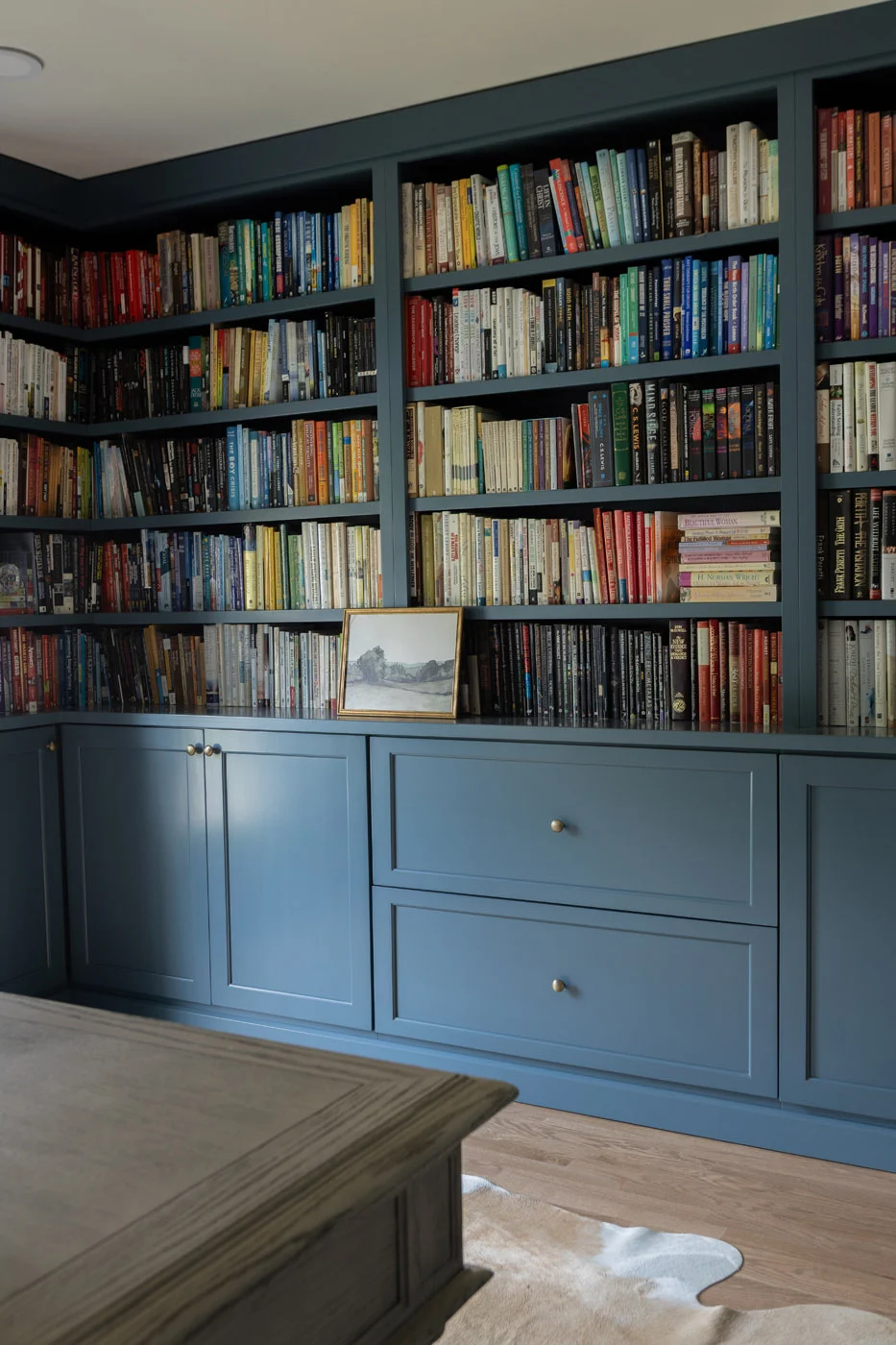 Riverview built-in library with slate-blue cabinetry and brass hardware