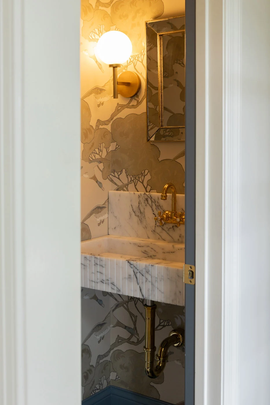 Riverview powder room with marble sink and patterned wallpaper